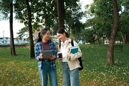 Young women students walking talking together on campus park