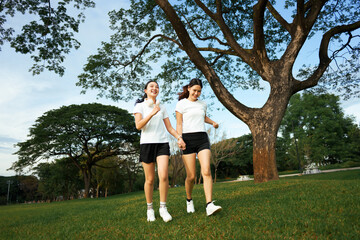 Happy Asian women friends jogging together in park