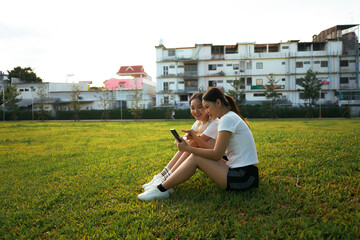 Women friends sharing content on smartphone in park
