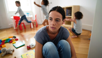 Exhausted woman in chaotic home environment, juggling parenting, emotional burnout, mental fatigue, messy living space, overwhelmed caregiver, everyday stressors, constant noise, tiredness, apathy