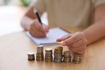 Woman counting coins at wooden table indoors, selective focus