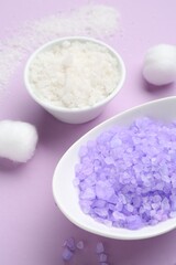Sea salt and cotton balls on violet background, closeup