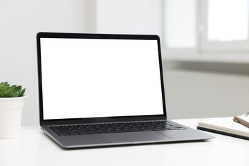 Fototapeta premium Laptop, notebook with pen and plant on white desk indoors. Mockup for design