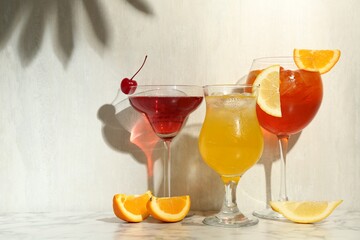 Glasses of tasty cocktails with garnish on white marble table, space for text