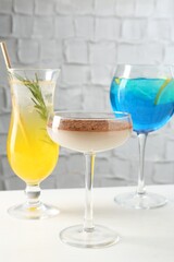Glasses of tasty cocktails on white table, closeup