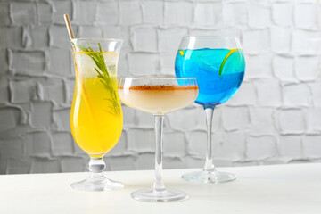 Glasses of tasty cocktails on white table