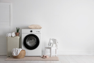 Laundry room interior with washing machine, basket and houseplant. Space for text