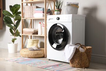Laundry room with modern washing machine, detergents and houseplants. Interior design