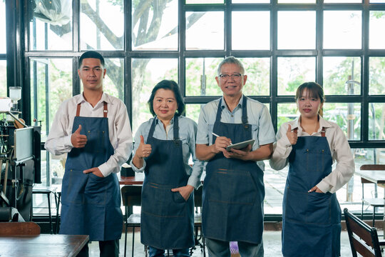 Asian restaurant team standing together smiling showing thumbs up including senior owners and young staff teamwork collaboration small business unity cafe family partnership success and service