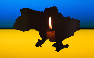 Ukraine blackout due to the war. A flickering candle is the sole source of light, placed near a map of Ukraine or a national flag. attacks on electric energy infrastructure by Russia