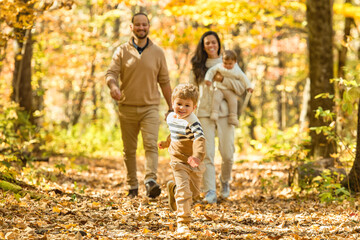 Fototapeta premium Beautiful young family on a walk in autumn forest