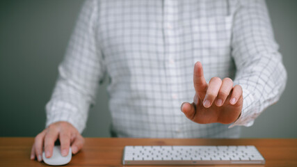 Businessman at his desk using a finger to touch an invisible virtual screen or holographic interface. This represents innovation, future technology, digital transformation, and interactive control.