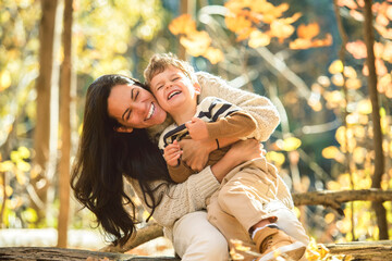 young mother with son in autumn in beautiful forest
