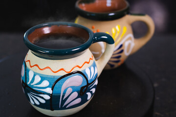 Traditional mexican coffee mugs filled with hot coffee and steam rising