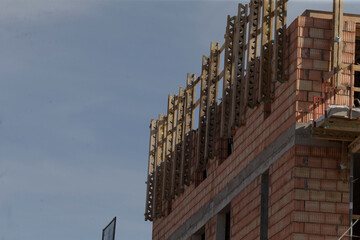 unfinished upper floor with timber formwork and safety rails framing window openings, raw brick...