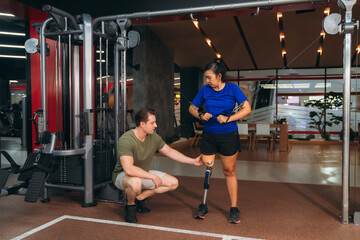 A female patient with a prosthetic leg receiving support from a physiotherapist during rehabilitation exercise, symbolizing recovery, care, and teamwork in modern medical and fitness therapy.