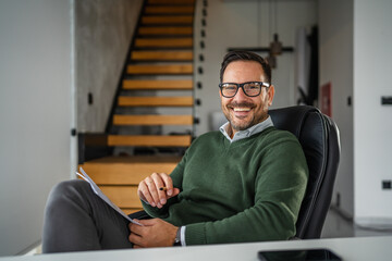 Smiling businessman portrait sitting at office desk happily