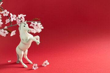 White horse with cherry flowers on a red background, celebration of the Chinese New Year 2026. Year of the horse