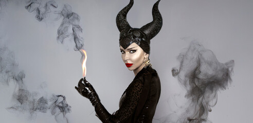 Dark queen with black horns and red lips in dramatic Halloween portrait Witch with smoke —...