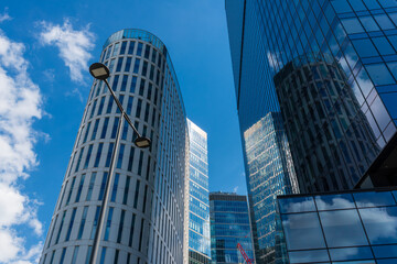 Obraz premium High-rise glass towers with modern design reflecting sky and clouds. The architecture symbolizes innovation, finance, and urban growth in a contemporary business district.