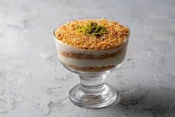 Traditional milky crispy Ramadan dessert custard pudding with roasted kadayif and diced pistachio . Kadayifi Muhallebi