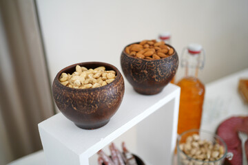 Peanuts and hazelnuts in ceramic bowls on a wooden stand.