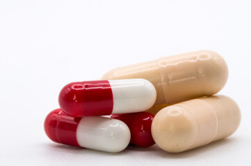 Several medicine capsules of different colors with a white background and copyspace