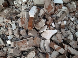 A pile of broken red bricks and fragments of concrete. Pile of debris of a torn down building