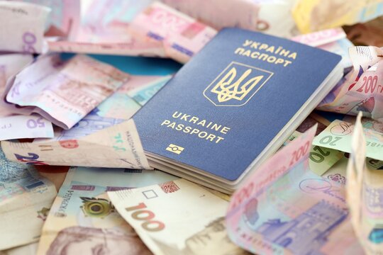 Ukrainian biometrical passport lies on big amount of different ukrainian hryvnia money bills - Powered by Adobe
