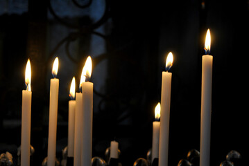 
a photo of several thin burning candles on a dark background