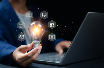 A businessman is holding a shining lightbulb that features learning icons for concepts in critical thinking, study skills, and problem-solving.