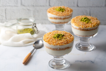 Traditional milky crispy Ramadan dessert custard pudding with roasted kadayif and diced pistachio . Kadayifi Muhallebi