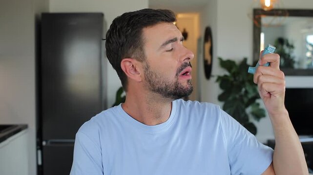 Asthmatic man using an inhaler at home 