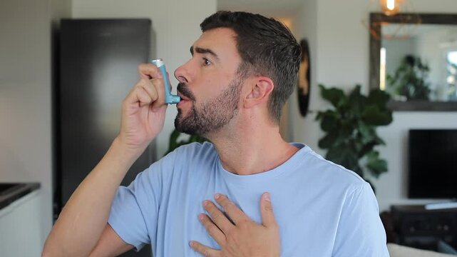 Asthmatic man using an inhaler at home 