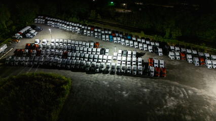 A night scene: A parking lot filled with parked cars under streetlights