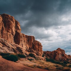 A landscape view of rugged red rock formations under a dramatic cloudy sky in a mountainous region
