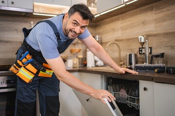 Technician smiling and checking dishwasher in a kitchen