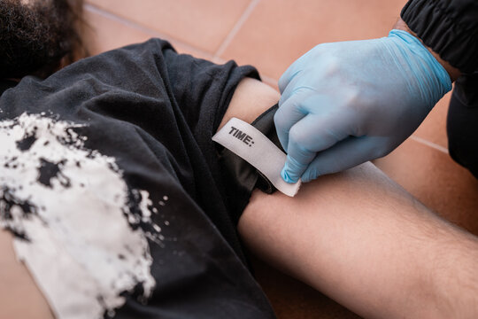 Paramedic placing tourniquet on injured man to stop bleeding during first aid