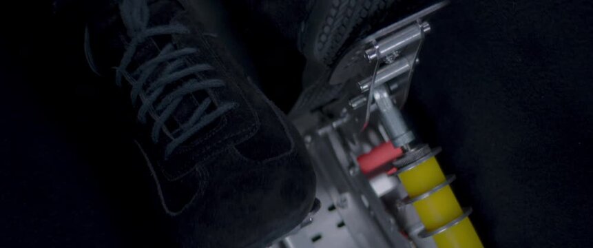 Close-up video of a race car drivers legs and feet engaging the pedals