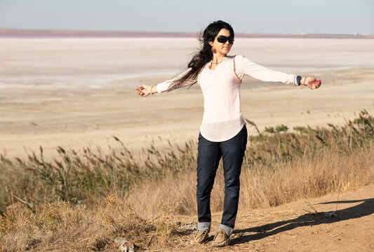 brunnet girl posing against real natural pink salted  lake at sunny day.  Crimea, Russia