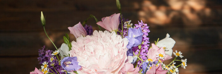 Vibrant floral bouquet with pink peony, purple and white flowers in sunlit setting.