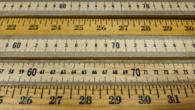 several vintage wooden rulers, showing measurements in centimeters and inches. Abstract precision, measurement, and craftsmanship background border. education and design.