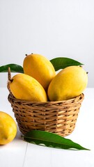 Basket of ripe yellow fruit with green leaves, set against a white backdrop