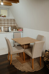Small rustic kitchen interior with a wooden dining table, beige chairs, and patterned tiles. Perfect for lifestyle, home, and real estate projects