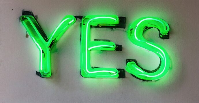 Bright green neon sign spells YES. Simple design, clean background. Positive affirmation, modern aesthetic. Bold letters illuminate space. - Powered by Adobe