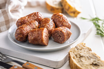 Photo of roasted italian sausage salsiccia on plate on white table.