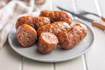 Photo of roasted italian sausage salsiccia on plate on white table.