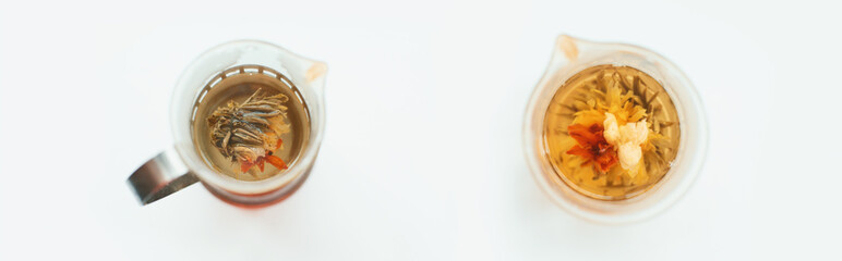 Top view of flowering tea bloom in glass teapot with clear hot water infusion.
