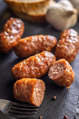 Photo of roasted italian sausage salsiccia on black table.