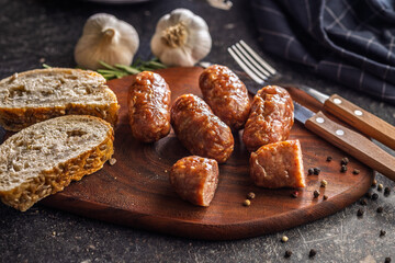 Photo of roasted italian sausage salsiccia on cutting board on black table.